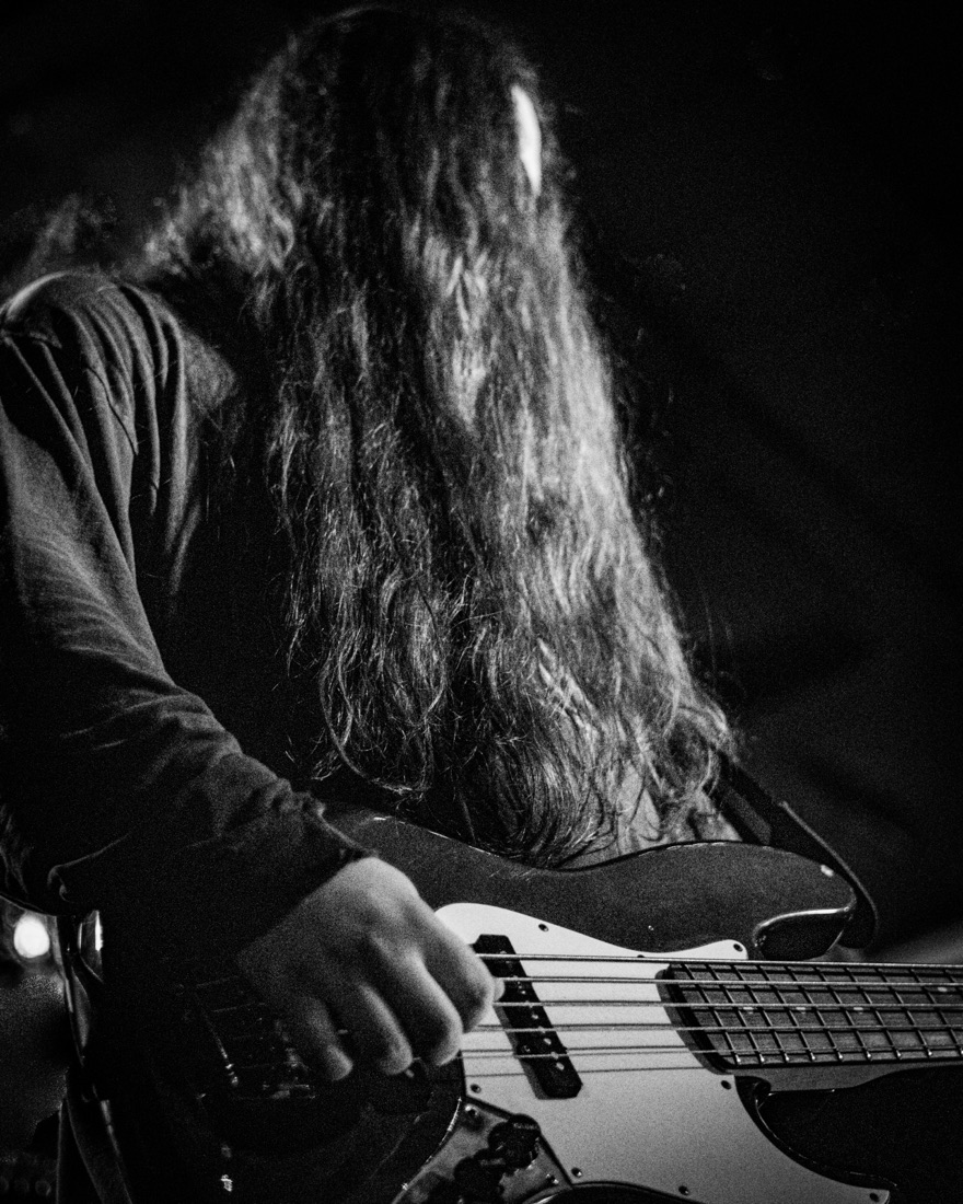 Bassist with long hair hanging over the bass, black and white