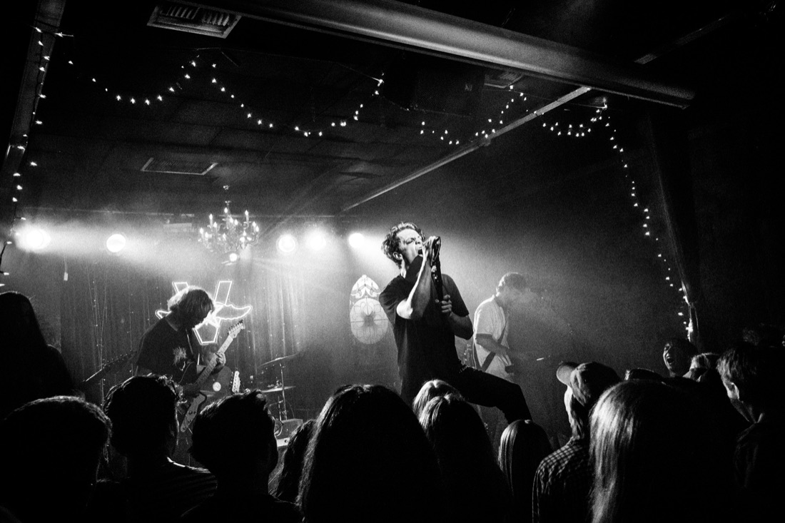 Vocalist screaming into the mic over the crowd, black and white