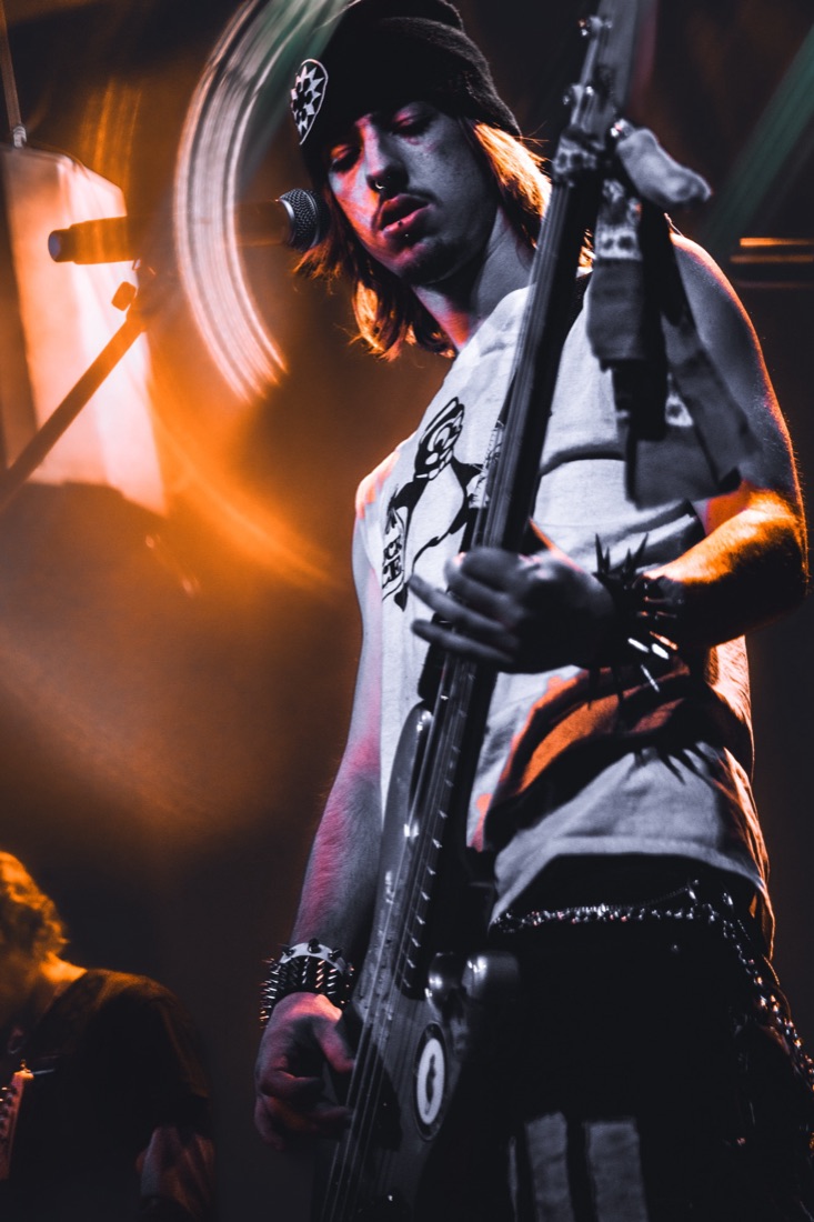 Guitarist in a bandana lit from behind by a warm stage light
