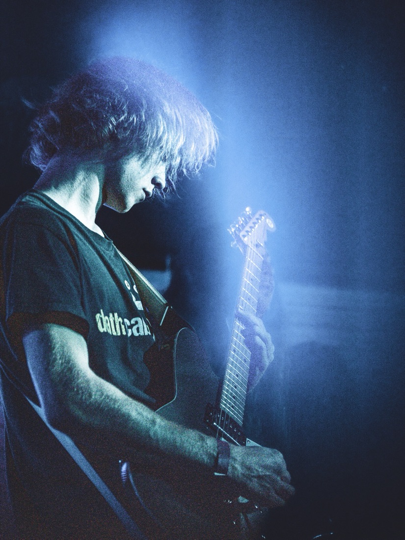 Guitarist leaning into a cold blue haze