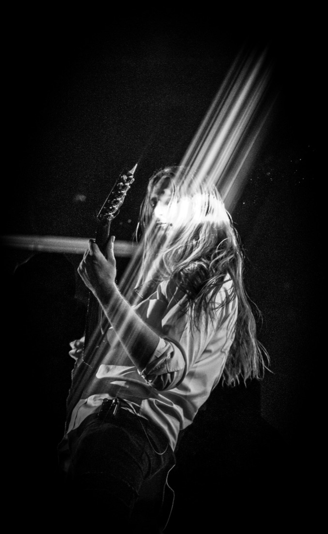 Guitarist lit by a beam of stage light, black and white