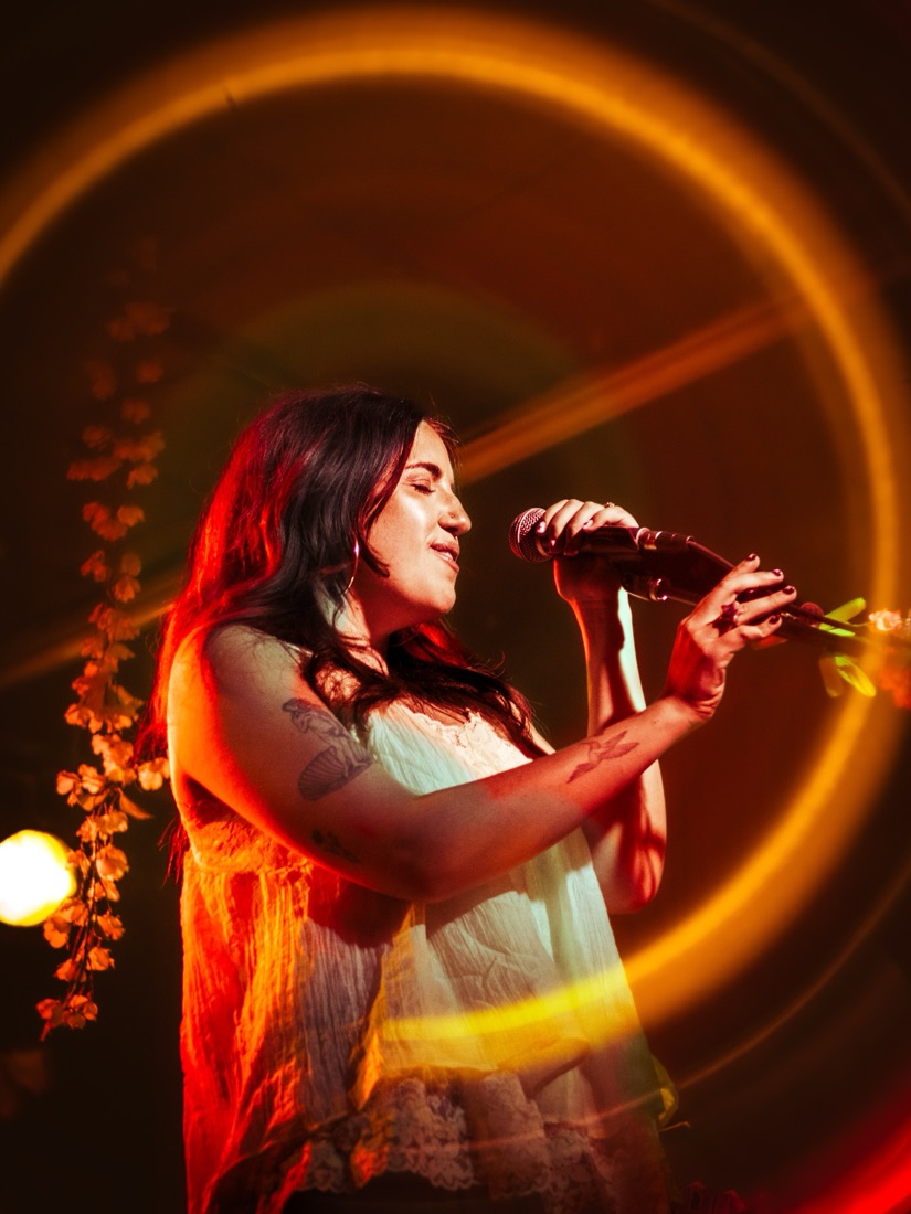 Singer holding a microphone inside a glowing orange ring of light